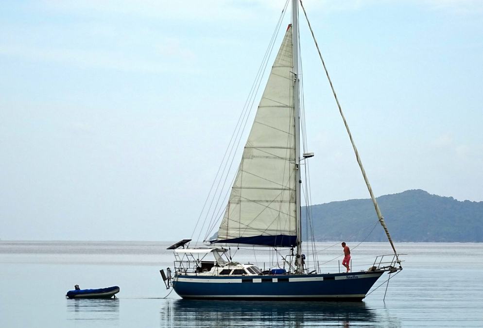 Ein Segelboot ankert vor den Hügeln der Bucht.