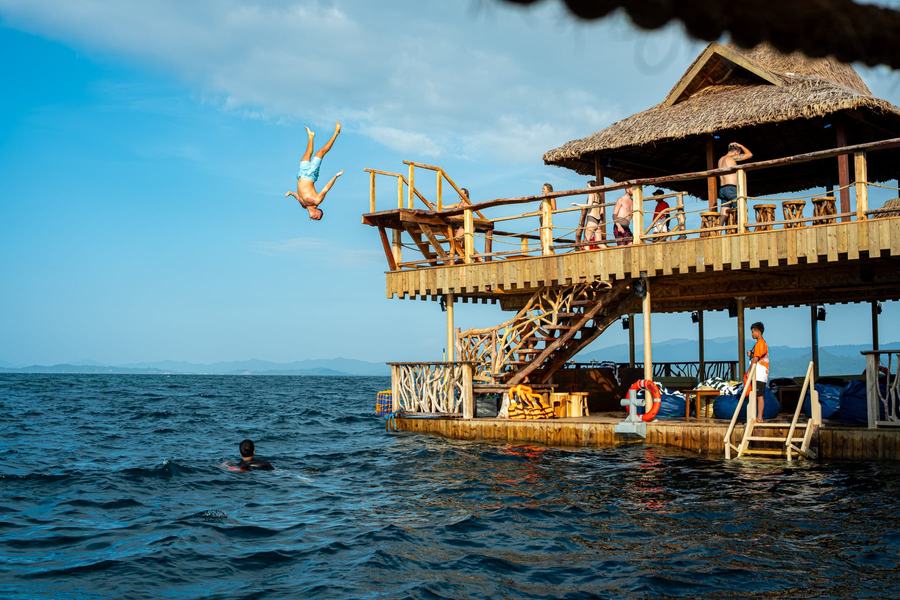 Ein Gast springt vom oberen Deck der Blue Ocean Bar ins Meer